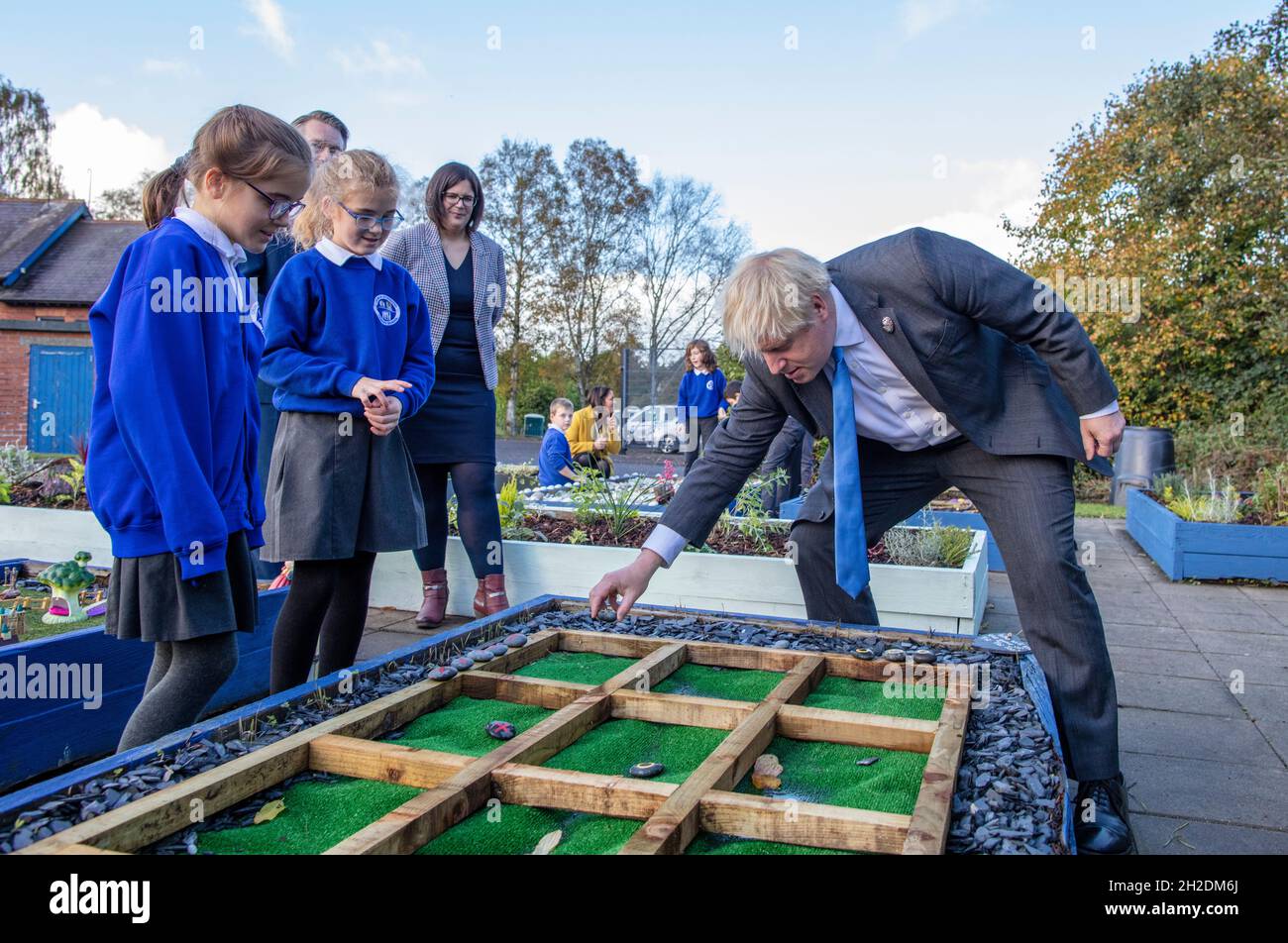Prime Minister Boris Johnson (right) joins schoolchildren playing a game of Tic Tac Toe in their sensory garden (which he wins) during a visit to Crumlin Intergrated primary school in County Antrim. Picture date: Thursday October 21, 2021. Stock Photo