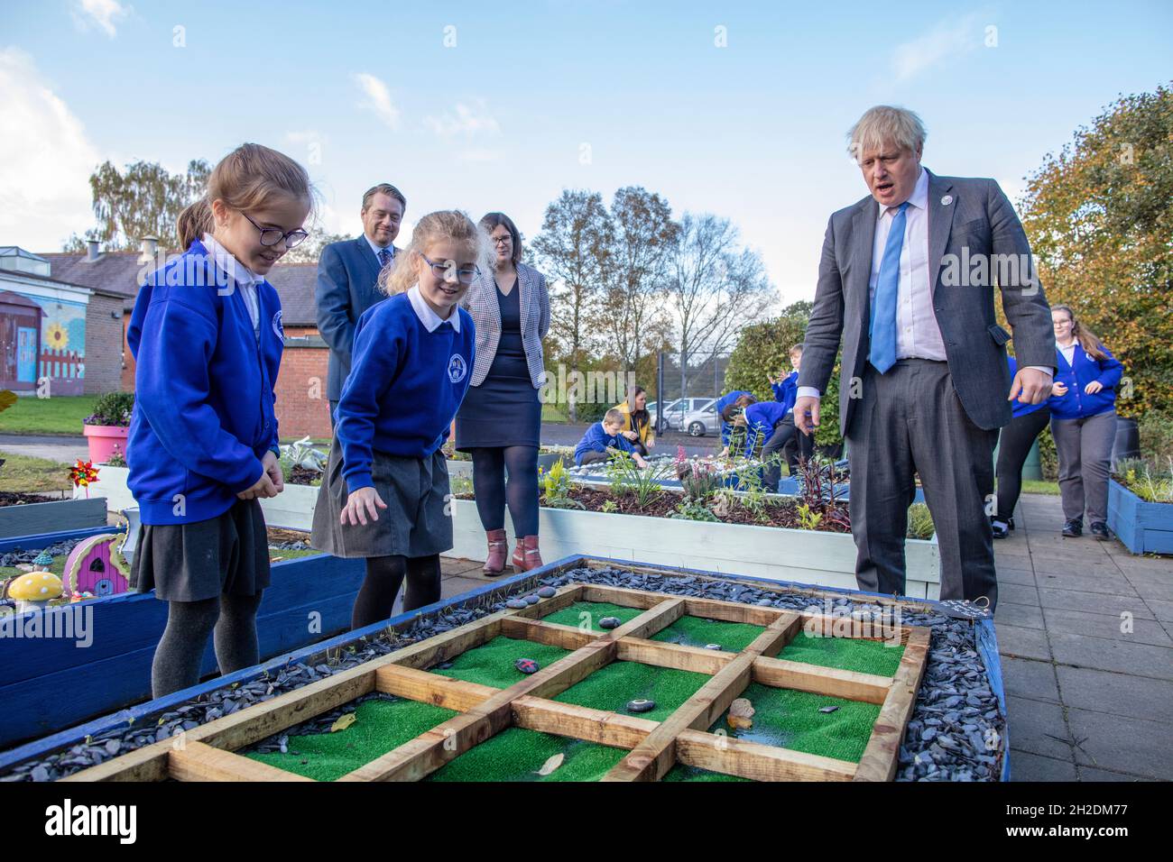 Prime Minister Boris Johnson (right) joins schoolchildren playing a game of Tic Tac Toe in their sensory garden (which he wins) during a visit to Crumlin Intergrated primary school in County Antrim. Picture date: Thursday October 21, 2021. Stock Photo