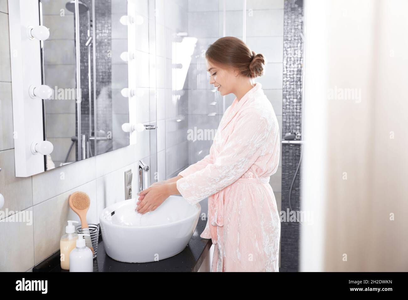 Young woman washing hands in bathroom. Using soap Stock Photo - Alamy
