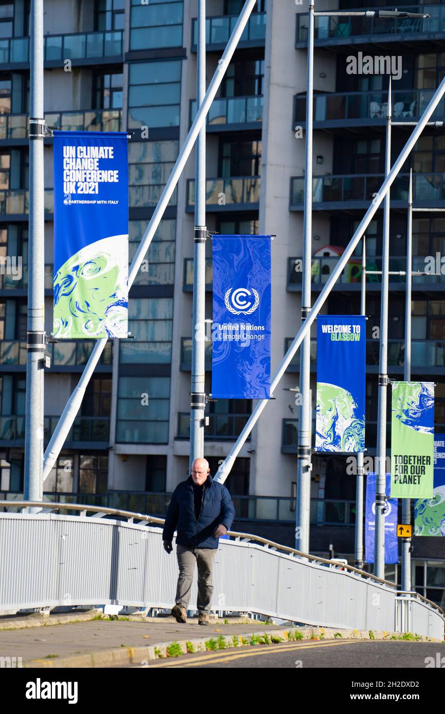 Glasgow, Scotland, UK. 21st October 2021. Final preparations underway at the site of the UN Climate Change Conference COP26 to be held in Glasgow from Oct 31st. Pic; Man walks below banners advertising COP26. Iain Masterton/Alamy Live News. Stock Photo