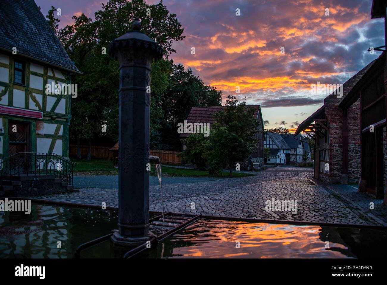 Timbering houses in a historic village under the colorful cloudy sky in the sunset Stock Photo