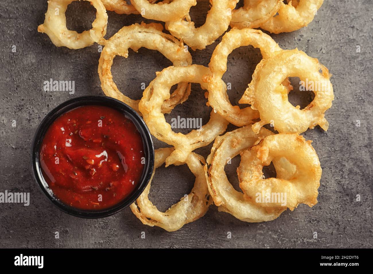 Delicious golden crispy onion rings and sauce on gray background, top ...
