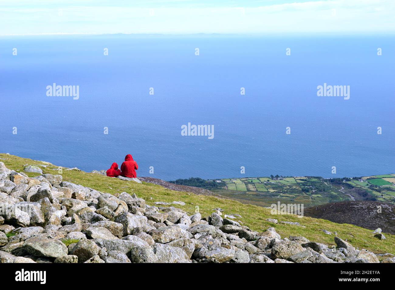 Couple of turists in red coats on the top of Slieve Donard mountain in Mourne Mountains, Northern Ireland Stock Photo