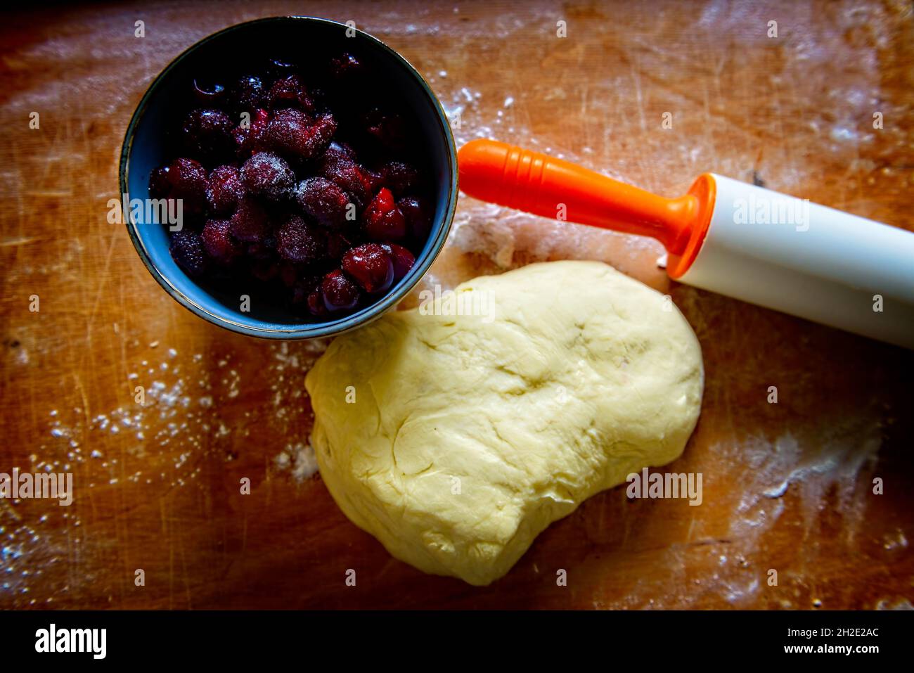 Making dumplings filled with sour cherry with sugar on a wooden cutting board Stock Photo