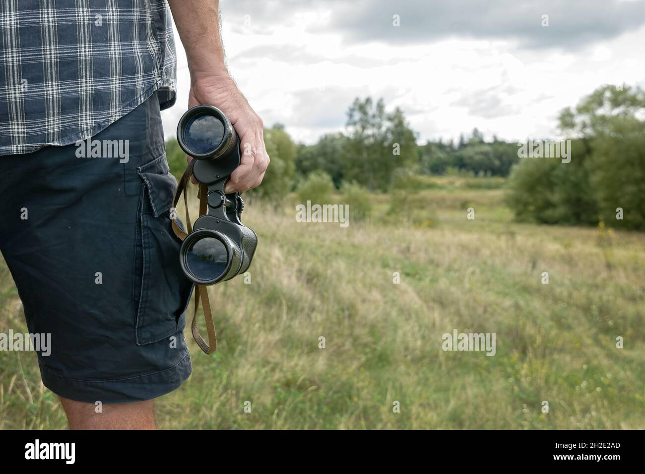 Man backpacker on the trail holding binoculars Stock Photo