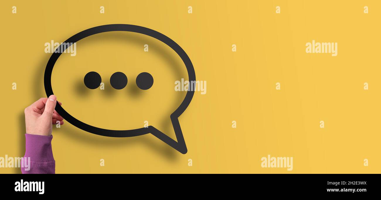 hand holding message symbol speech bubble against yellow background Stock Photo