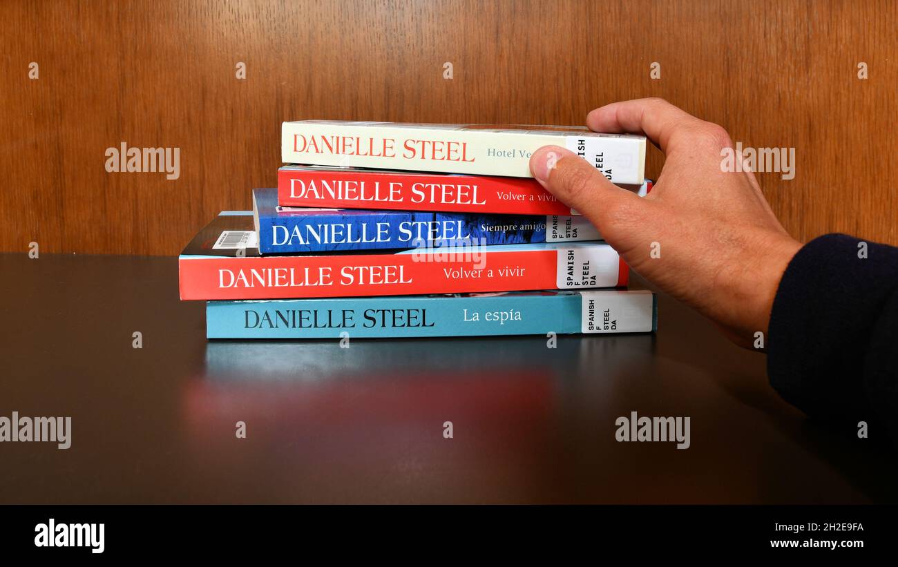 Man's hand reaching for a book by Danielle Steel; Spanish translation of the author's novels Friends Forever, Fall from Grace, Hotel Vendome, Spy. Stock Photo