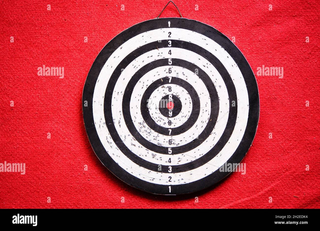 Used dart board standing on red carpet and its shadows. Stock Photo
