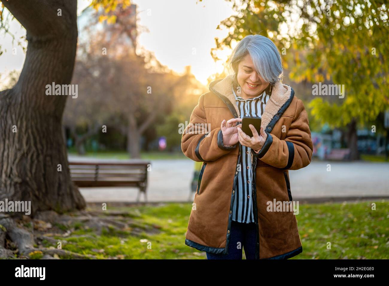 Mature woman using smart phone outdoor at the park Stock Photo - Alamy