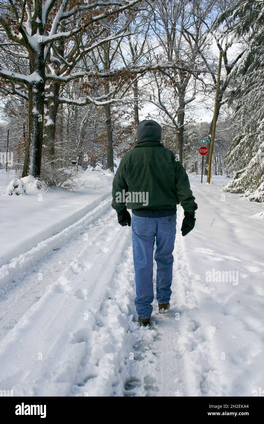 A bundled up man walks through a scenic landscape of fresh snow Stock Photo