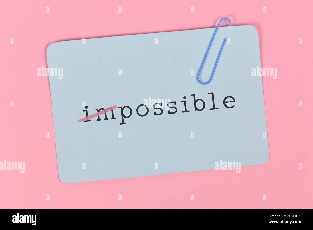Word impossible changed into word possible on blue card on pink background Stock Photo
