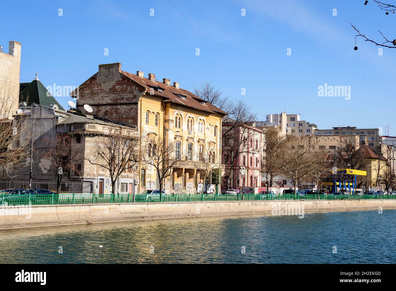 Bucharest, Romania, 13 February 2021 - Landscape with large old trees and old buildings near Dambovita river and clear blue sky in the center of Bucha Stock Photo