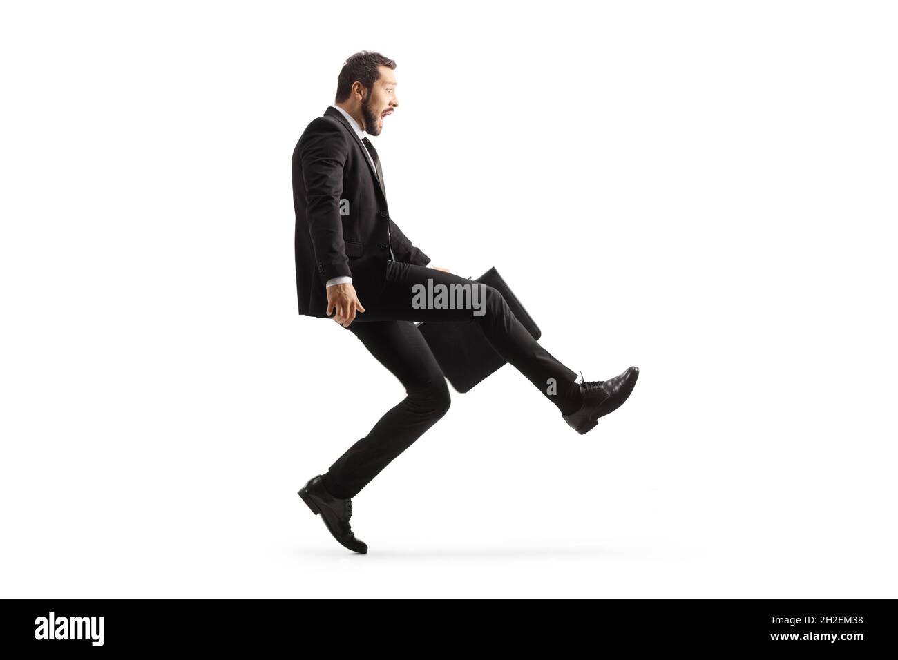 Full length profile shot of a businessman with a briefcase walking silly on tiptoes isolated on white background Stock Photo