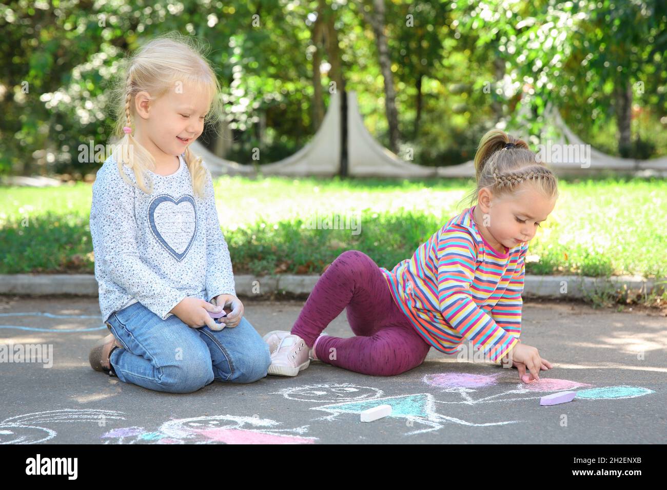 Little children drawing with colorful chalk on asphalt Stock Photo - Alamy