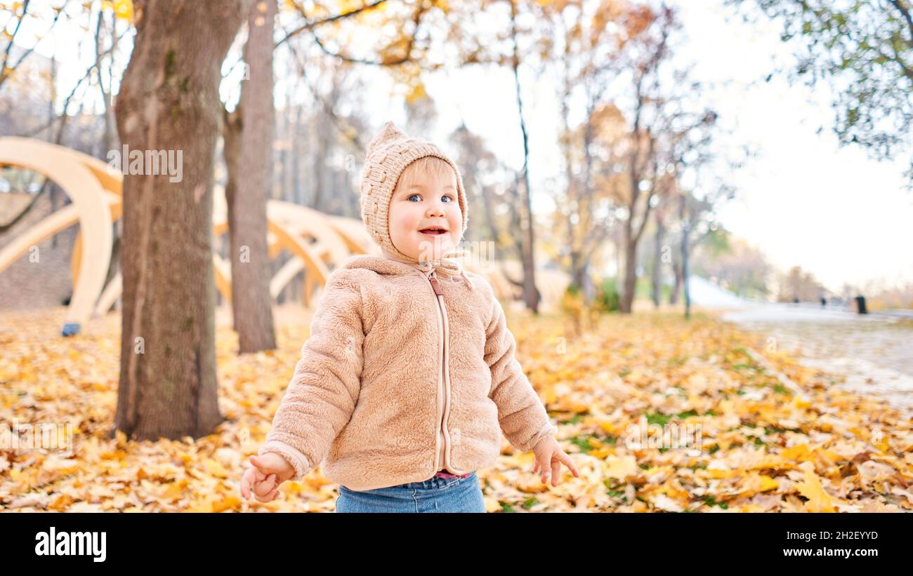 Yellow Autumn Park. Leaf fall and yellow leaves. Portraits of a cute 1 year old baby girl. sunny day. Stock Photo