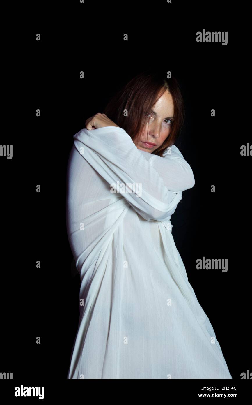 Concept of mental problems and mental health. Portrait of a woman in a white straitjacket with a mad sad look Stock Photo
