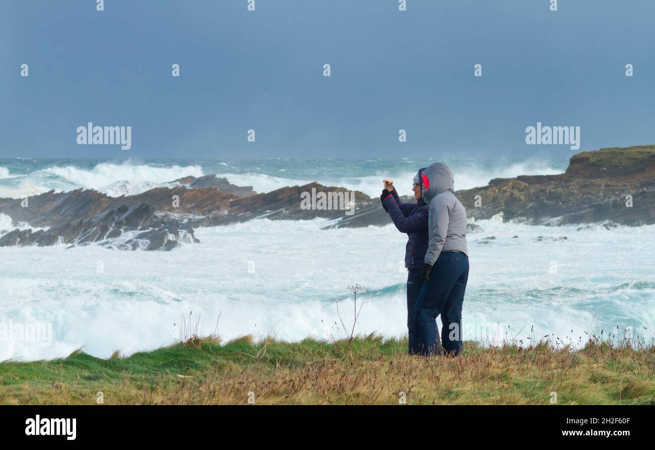 Woman taking smartphone photograph of rough seas, Orkney islands Stock Photo