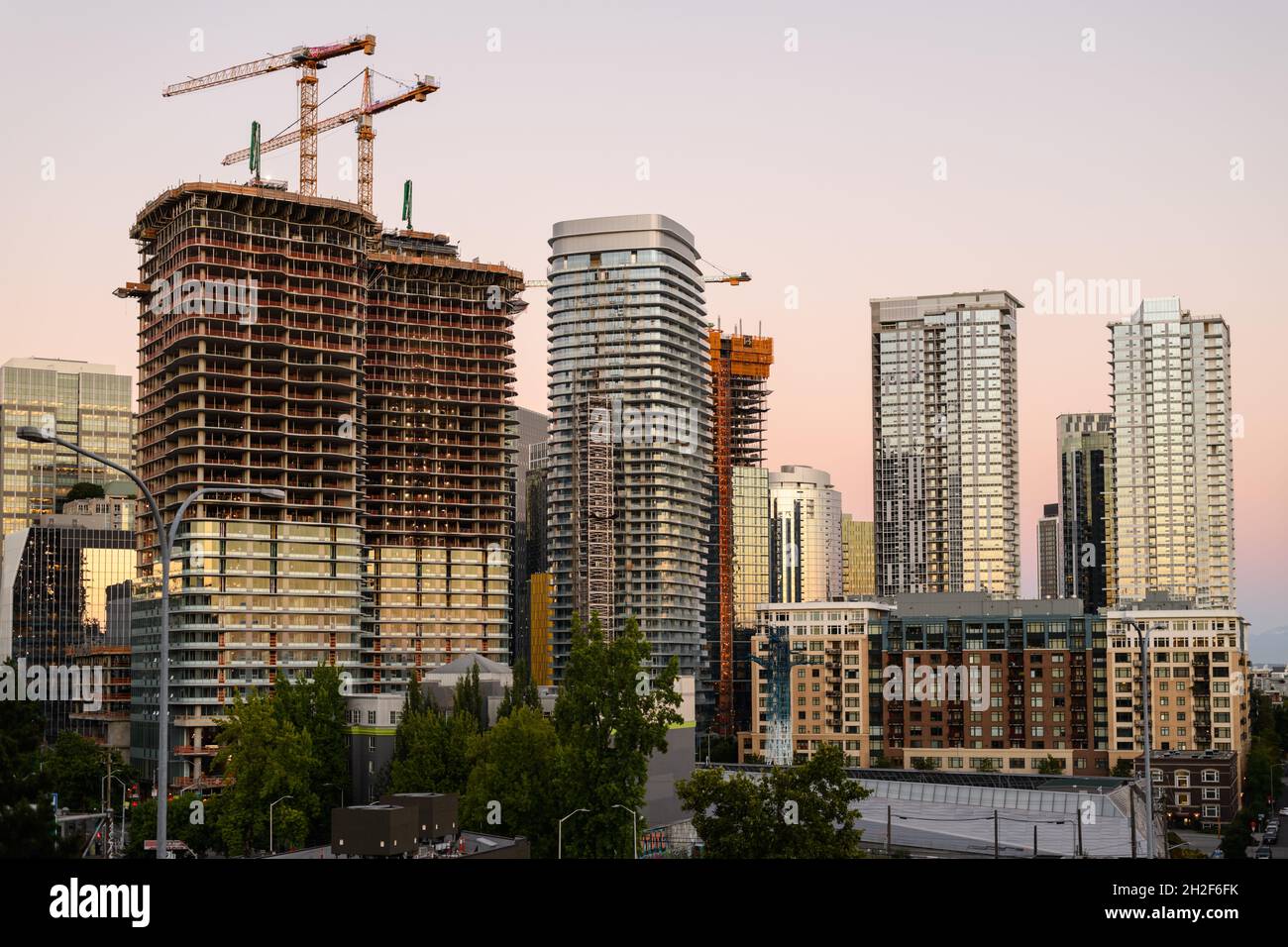Seattle - July 25, 2021; Construction cranes rise above tall buildings in the downtown core of Seattle at sunrise Stock Photo