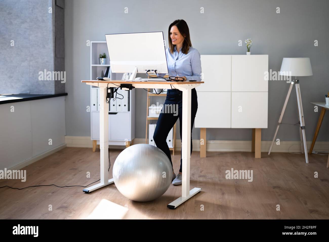 Woman Using Adjustable Height Standing Desk In Office For Good Posture Stock Photo Alamy