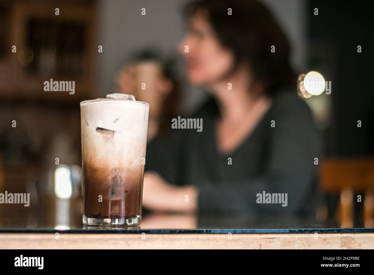 Drinking iced coffee at the table with middle age white woman Stock Photo