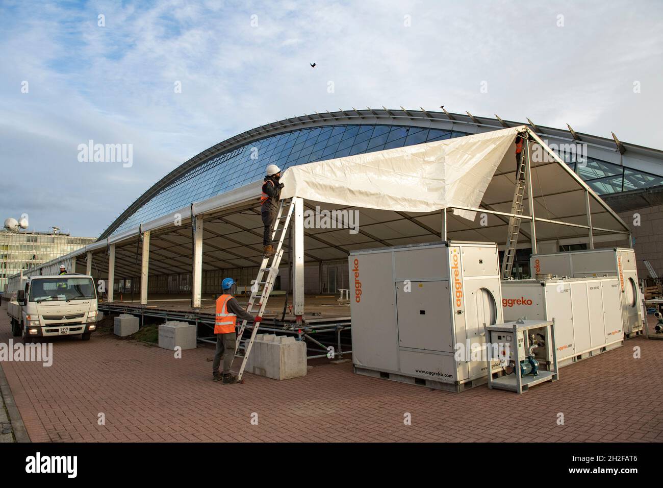 Glasgow, Scotland, UK. 21st Oct, 2021. PICTURED: Workmen continue to construct the large tent like temporary structures, this one being outside of the Science Centre. 10 days until the start of COP26. The COP26 site showing temporary structures half built on the grounds of the Scottish Event Campus (SEC) Previously known as Scottish Exhibition and Conference Centre (SECC). Security fences with a ‘ring of steel' encapsulates the COP26 conference site. CCTV stations with emergency lights and loudspeakers are positioned all over the site. Credit: Colin Fisher/Alamy Live News Stock Photo