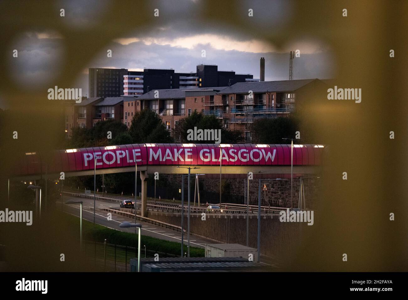 Glasgow, Scotland, UK. 21st Oct, 2021. PICTURED: The People Make Glasgow sign which adorns the pedestrian walkway spanning over the Clydeside Expressway at the back of the COP26 site. 10 days until the start of COP26. The COP26 site showing temporary structures half built on the grounds of the Scottish Event Campus (SEC) Previously known as Scottish Exhibition and Conference Centre (SECC). Security fences with a ‘ring of steel' encapsulates the COP26 conference site. CCTV stations with emergency lights and loudspeakers are positioned all over the site. Credit: Colin Fisher/Alamy Live News Stock Photo
