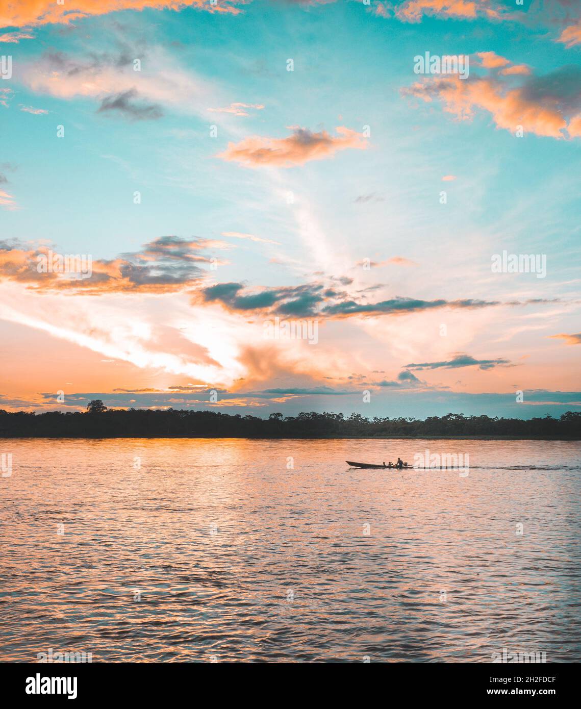 Boat meanders forward during surreal sunset on the river Stock Photo