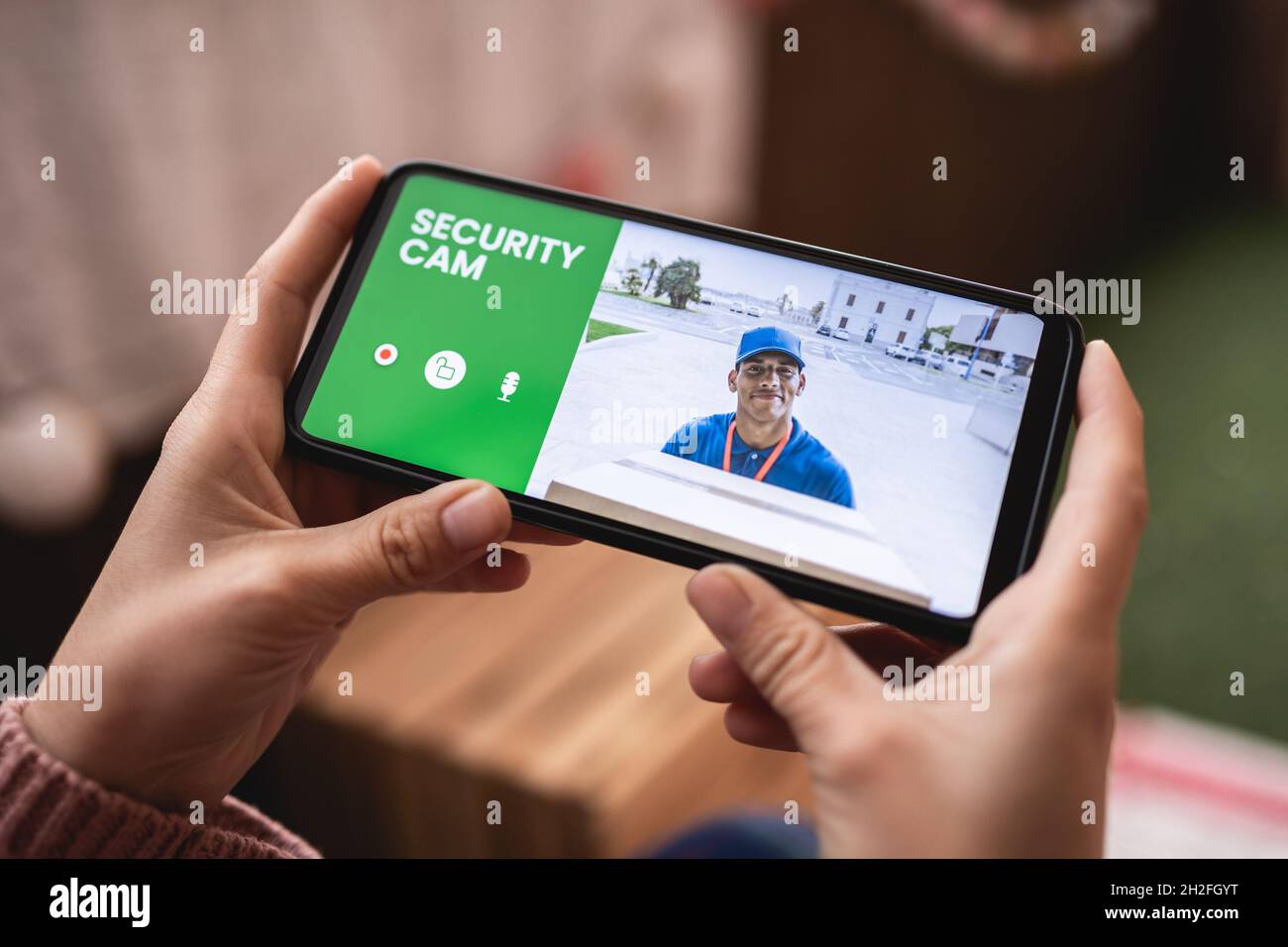 Woman watching delivery man through security camera system on mobile phone at home - Cctv smart technology lifestyle concept Stock Photo