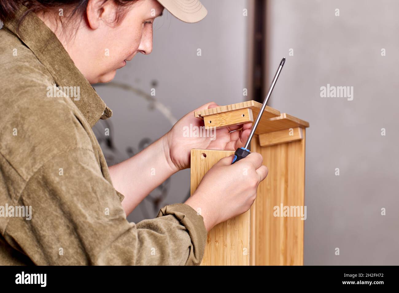 Assembler is installing drawer of flat pack furniture using tool. Stock Photo