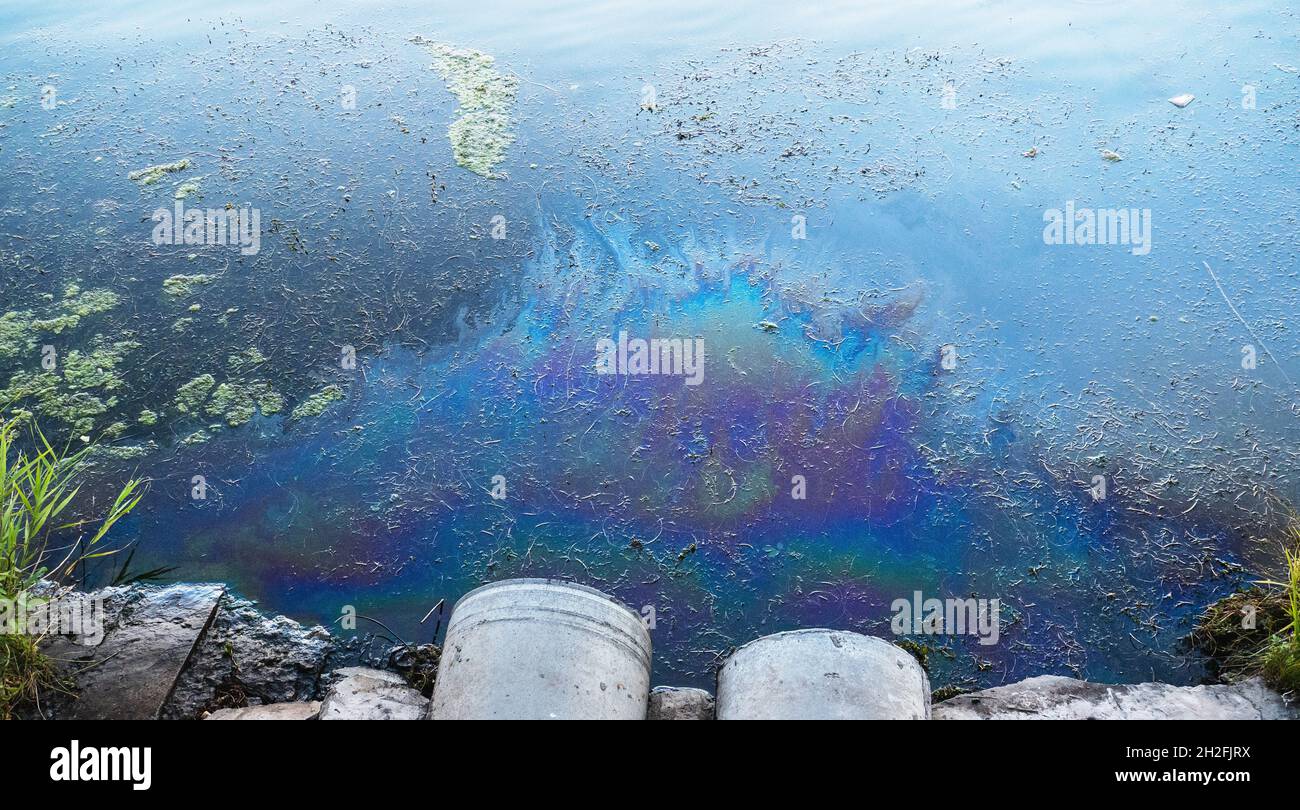 Toxic oil or petroleum pollution of ocean or river water from waste water pipe. Stock Photo