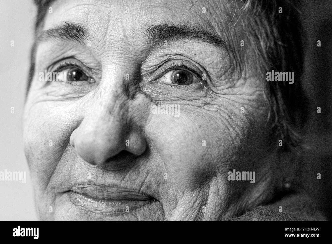 Grayscale shot of an old smiling Hispanic woman Stock Photo