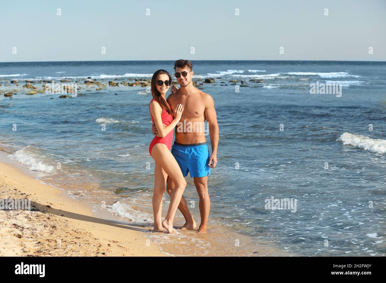 Happy young couple posing near sea on beach Stock Photo | Adobe Stock