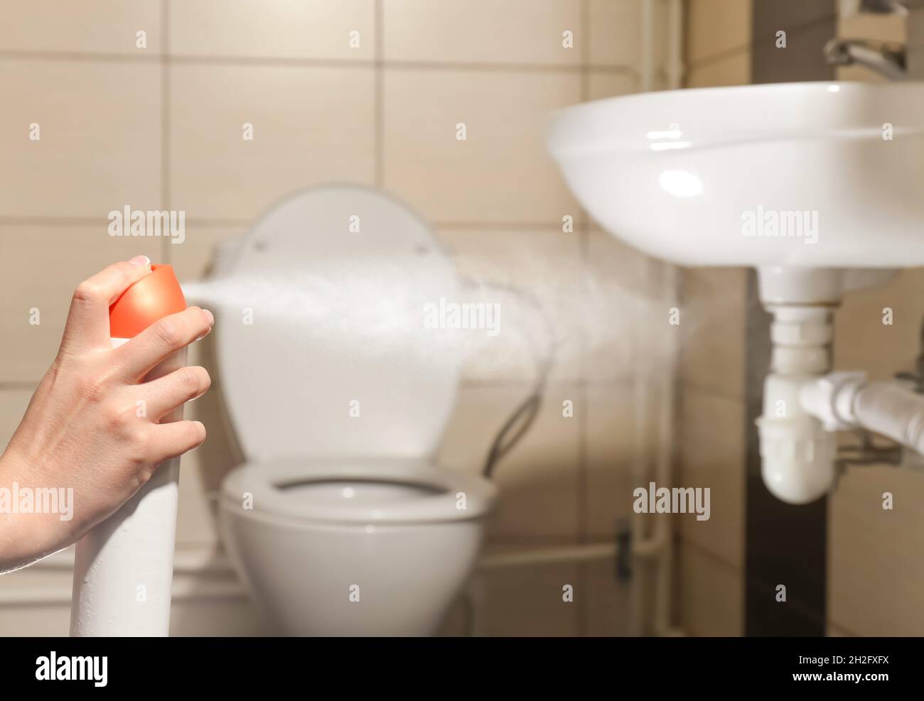 Woman spraying air freshener in bathroom Stock Photo Alamy