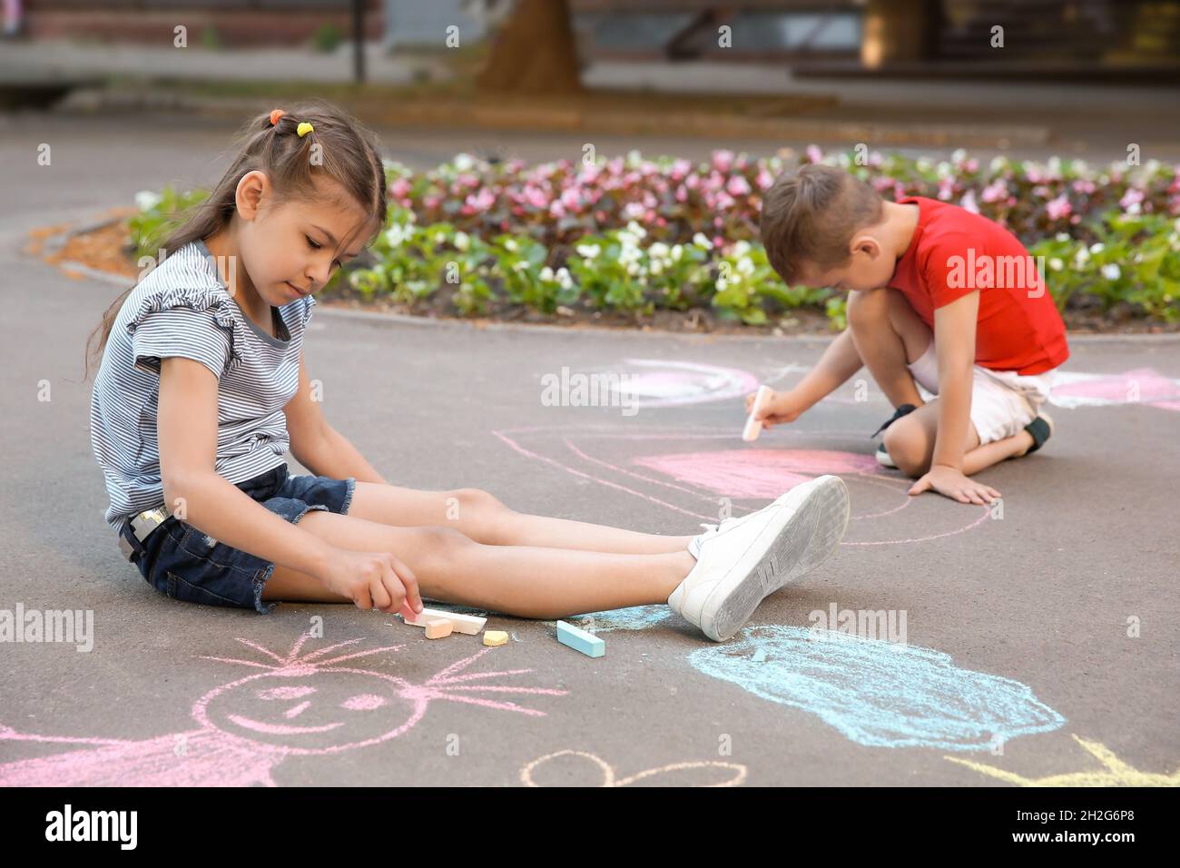 Little children drawing with colorful chalk on asphalt Stock Photo - Alamy