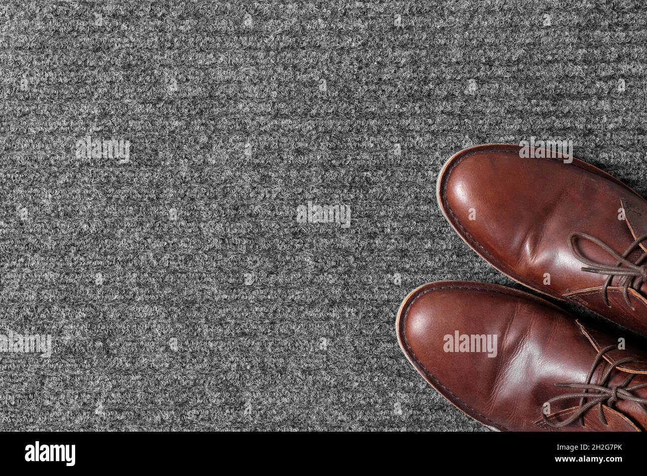 Brown classic shoes on gray doormat, top view. Space for text Stock Photo