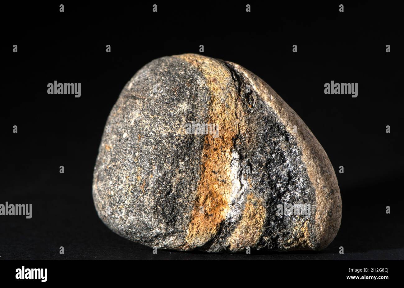 Single stone with red and brown geological pattern isolated on black background Stock Photo