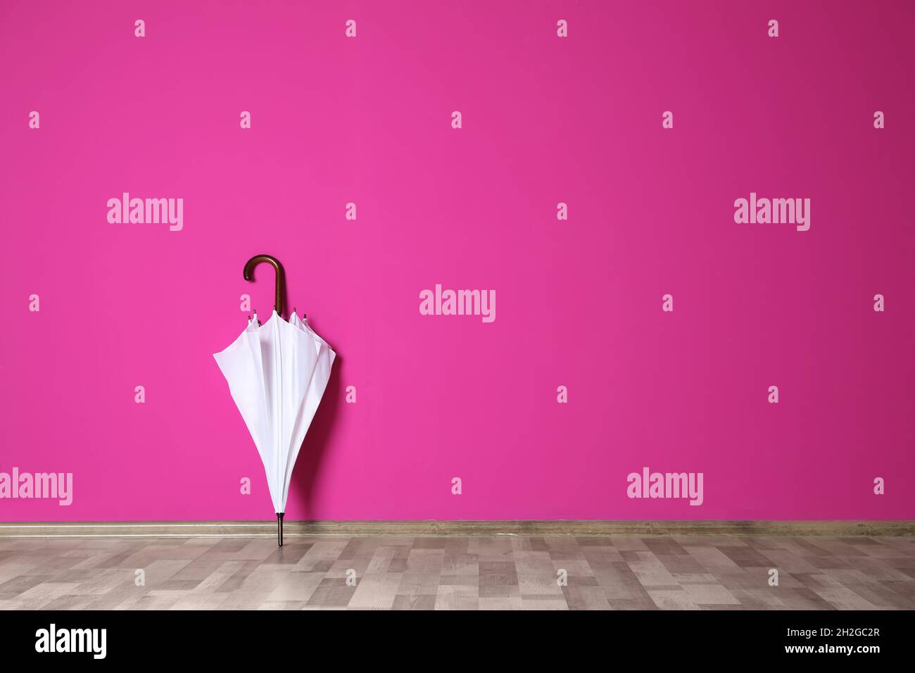 Beautiful umbrella on floor near color wall with space for design Stock