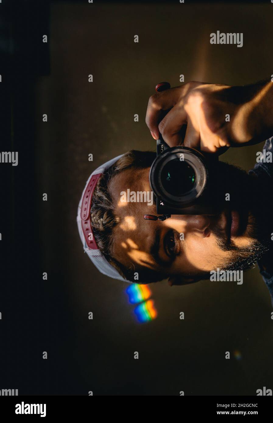 selfie while looking in the mirror . Rainbow light in the background. Stock Photo