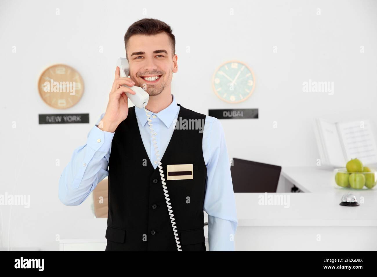 Male receptionist talking on phone at workplace in hotel Stock Photo
