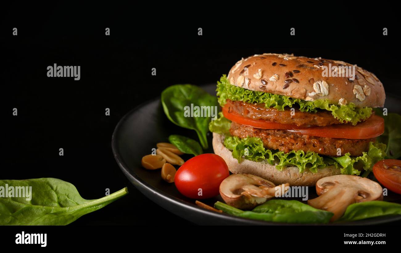 Plant based burger with fresh and organic vegetables on a plate in black background. Healthy food concept Stock Photo
