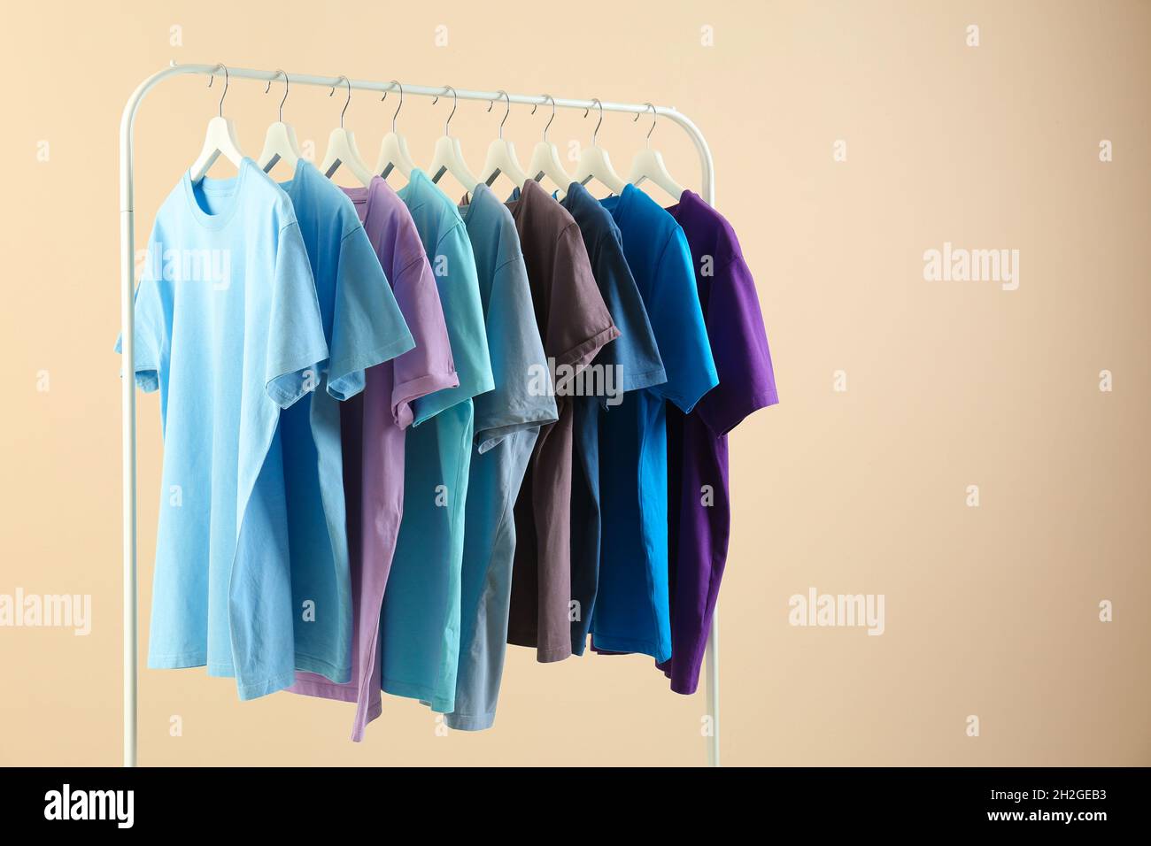 Men's clothes hanging on wardrobe rack against light background Stock