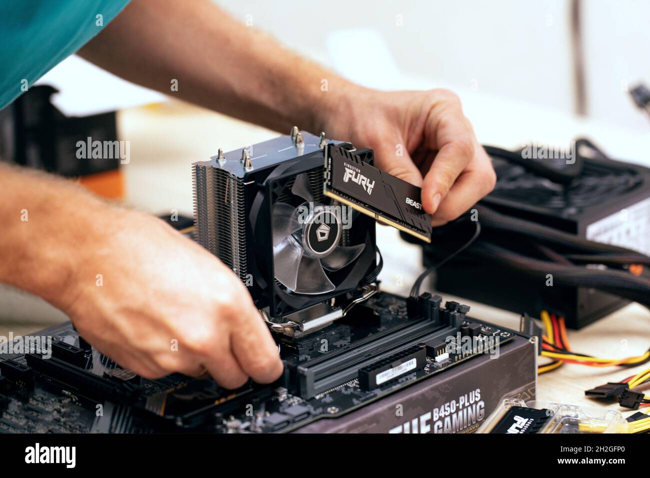 Cropped image of man installing Fury Beast random access memory DDR4 stick on motherboard of professional PC for cryptocurrency mining. Russia, 17.08. Stock Photo