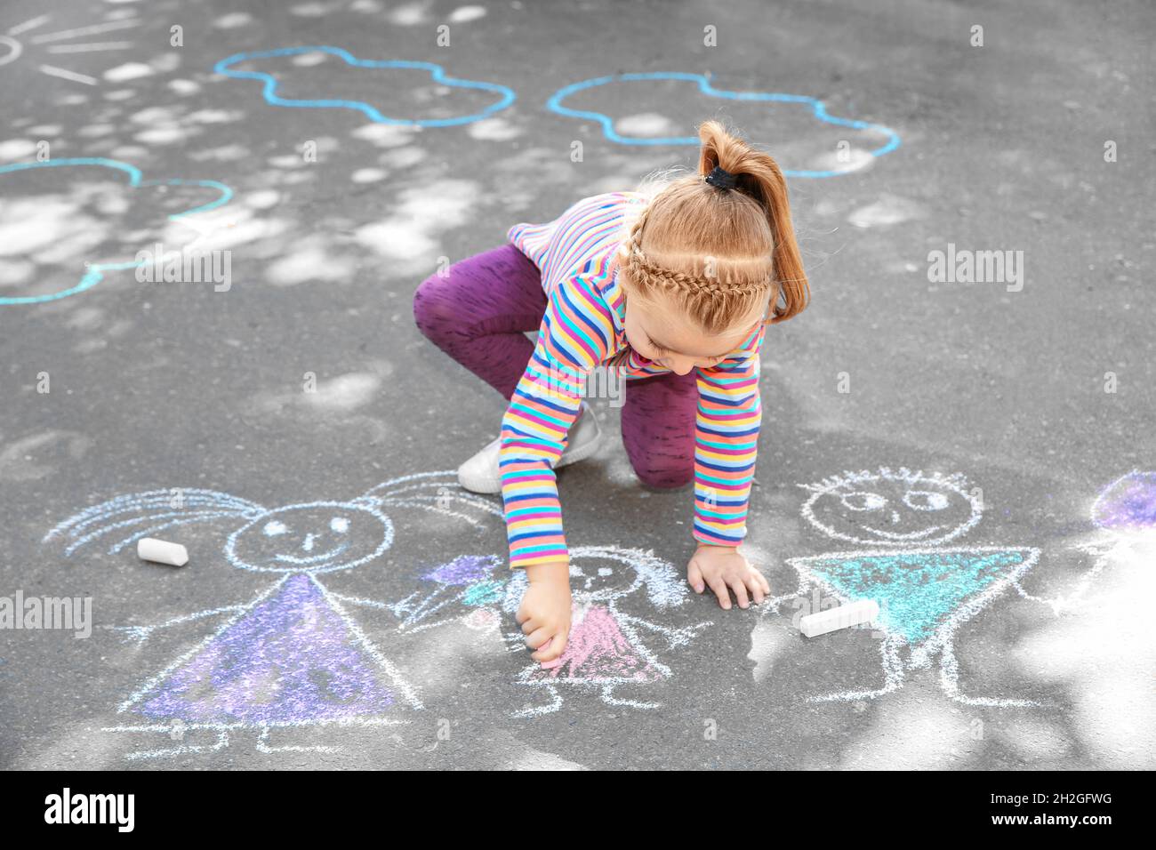 Little child drawing with colorful chalk on asphalt Stock Photo - Alamy