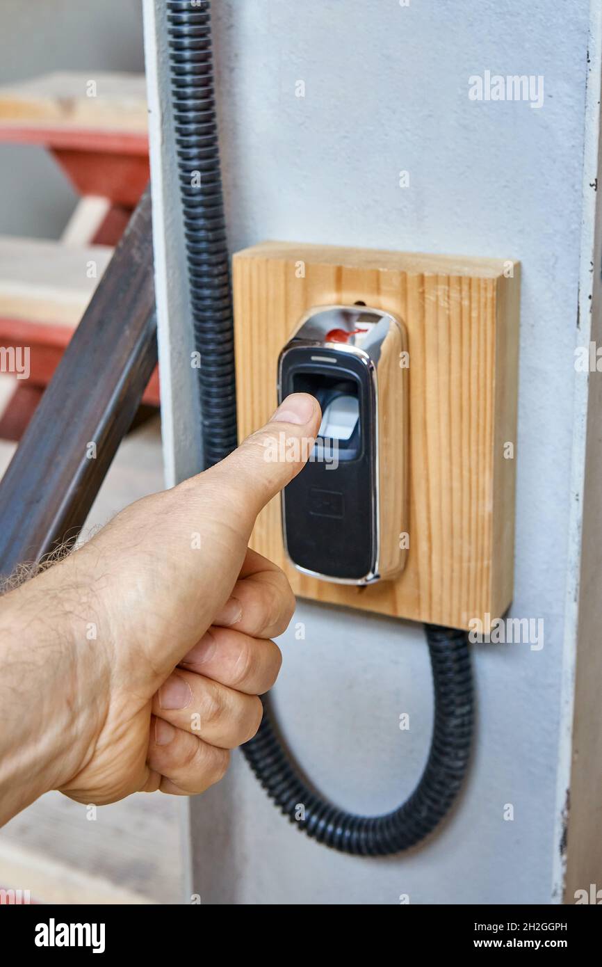 Worker uses contemporary biometric fingerprint scanner to record shift ...