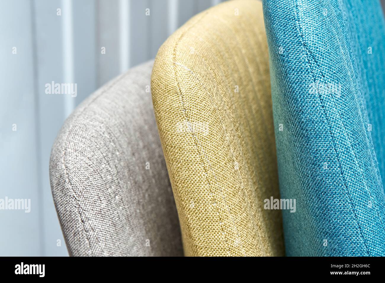 Colorful soft backs with vertical stitching of modern office chairs in light furniture assembling workshop at plant extreme closeup Stock Photo