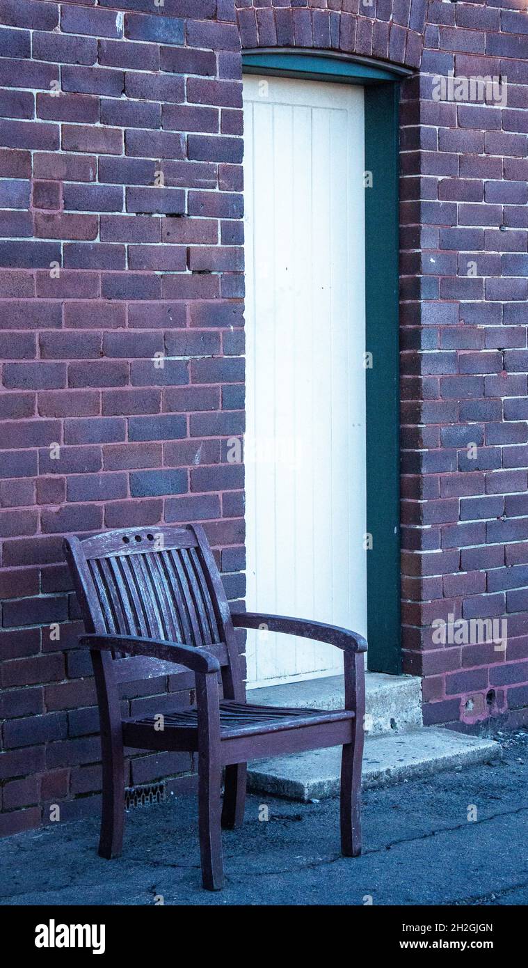 Single waiting chair outside doorway set in old brick building Stock Photo
