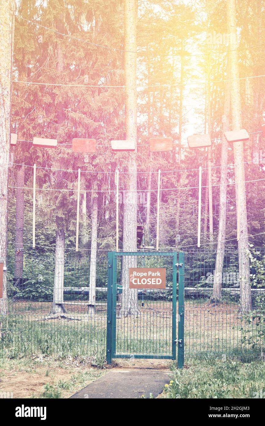 Rope park with empty high rope courses on old pine trees and grid fence ...