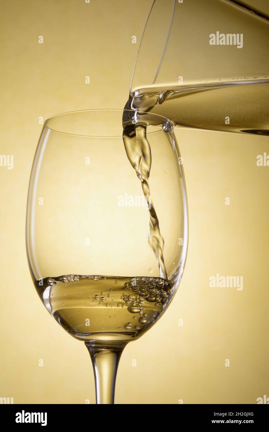 Pour white wine from a carafe into a glass Stock Photo