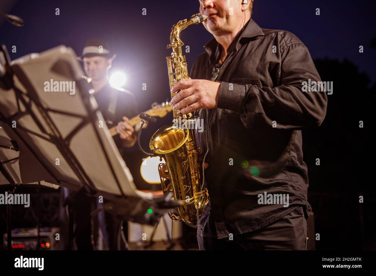 Saxophone player playing in orchestra at night outdoor concert Stock