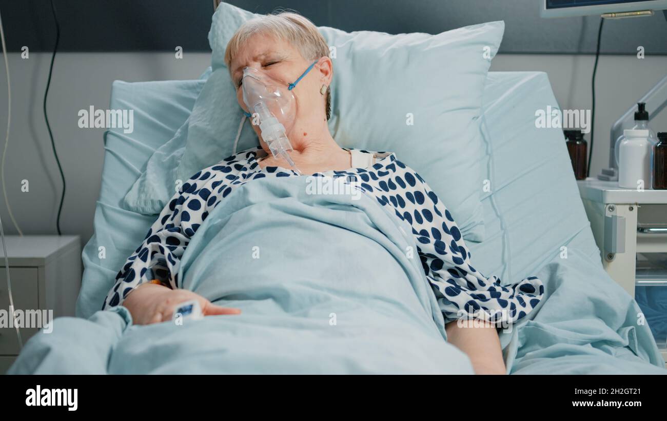 Retired woman with oxygen tube against respiratory problem in hospital ward  bed. Sick patient breathing heavily while resting and waiting for medical  assistance with IV drip bag Stock Photo - Alamy